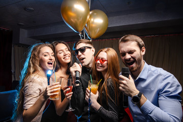 young caucasian people celebrating birthday in karaoke bar, chill out. holiday, celebration, party concept. emotional pastime