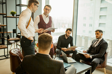 Wall Mural - brainstorming of caucasian business crew consisted of young men leaders dressed in formal wear, in tuxedo gathered to share experience and opinion, discuss, develop business strategies and plans