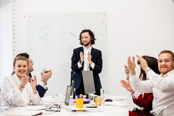 Wall Mural - young boss man and colleagues applause to each other for good job, successful ending of project, isolated in business office