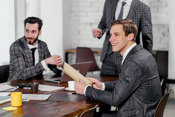 Wall Mural - young men in suits gathered in business meeting for discussing together business strategies, developing new strategy for future year or month