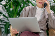 © alfa27 - Closeup view on laptop hold by senior businesswoman talking on phone. Female wearing elegant clothes, plants background