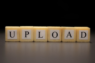 The word UPLOAD written on wooden cubes isolated on a black background...