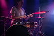 © puhimec - The drummer plays the drums. Beautiful blue and red background, with rays of light. Beautiful special effects smoke and lighting. The process of playing a musical instrument. Close-up photo.