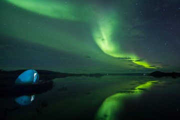 Wall Mural - Aurora Borealis (Northern lights) above a camping tent in the Icelandic wilderness near lake