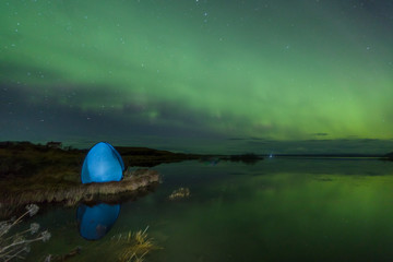 Wall Mural - Aurora Borealis (Northern lights) above a camping tent in the Icelandic wilderness near lake