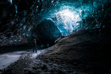 Wall Mural - Female explorer inside ice cave tunnel, Iceland
