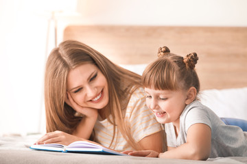 Sticker - Beautiful young woman and her little daughter reading book at home