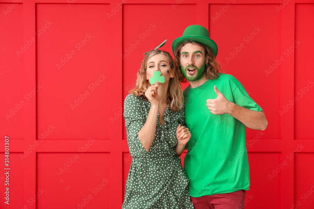 Young couple on color background. St. Patrick's Day celebration