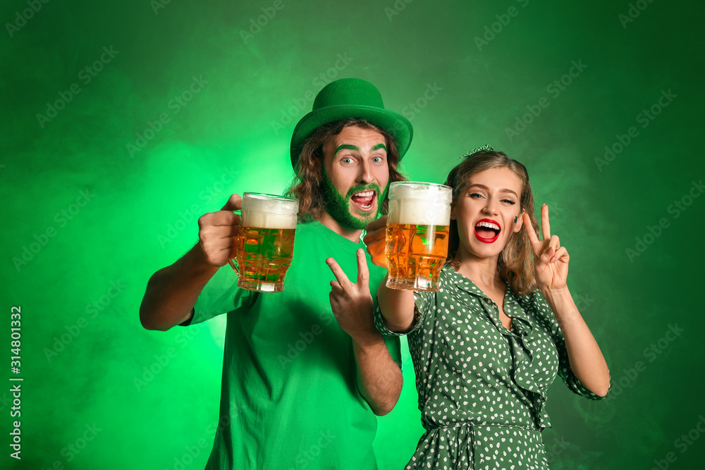 Young couple with beer on color background. St. Patrick's Day celebration
