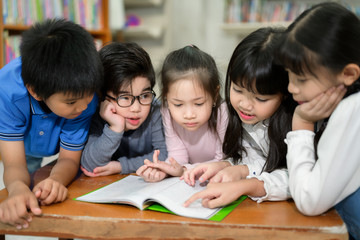 Wall Mural - A Group of Asian Kids Reading Book in School Library with a Shelf of Book in Background, Asian Kid Education Concept