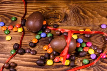 Chocolate easter eggs and multicolored candies on wooden table