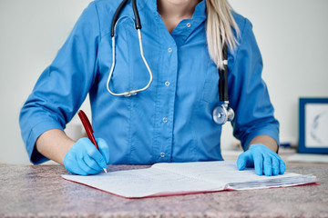 Closeup of young vet doctor writing diagnosis in special folder