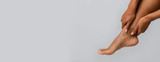 Woman rubbing her injured ankle over grey background