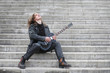 © alexkich - Rock guitarist on the steps. A musician with a bass guitar in a leather suit. Metalist with a guitar on the background of industrial steps.