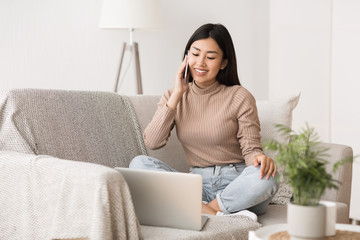 Poster - Multitasking concept. Girl using laptop and talking on cellphone