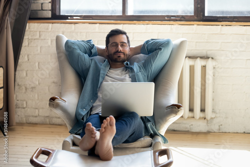 Cuadros en Lienzo Serene barefoot guy resting, daydreaming at home.