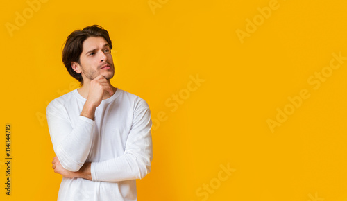 Fotografía Doubtful man thinking about something, touching chin with thoughtful face expres