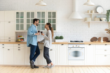 Mixed race spouse standing in kitchen with glasses of wine.