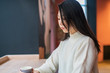 A mysterious, thoughtful, modest young Korean woman with natural beauty is sitting in a cafe in the morning.