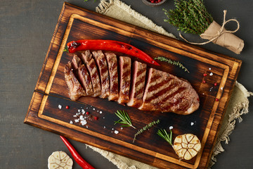 Keto ketogenic diet beef steak, grilled fried striploin on cutting board on dark brown table