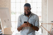 © fizkes - Smiling biracial male employee using cellphone in office boardroom