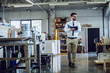 © Dusan Petkovic - Full length of young caucasian bearded supervisor in shirt and tie and with eyeglasses walking around printing shop. All around are stacks with sheets and machines.