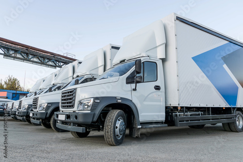 Five white truckers in the parking lot are waiting for the next delivery of goods. The concept of a transport company for the delivery of goods around the world. View from the back. Isolate