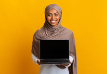 Afro Muslim Girl In Headscarf Holding Laptop Computer With Black Screen