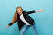 © Ivan Traimak - Beautiful caucasian teenager girl in black jacket and jeans dances isolated on blue background