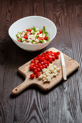 Poster - Cherry tomatoes with salad cheese on cutting board on wooden table. Cooking vegetable salad