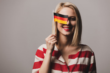 beatiful girl holds german flag on gray background