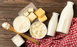 Dairy sour milk products on a wooden dark rustic background. Milk, kefir, yogurt, butter, cheese assortment. Flat layout