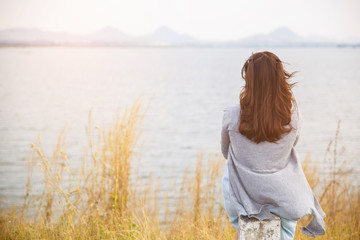 Back view of woman sit on the side of road with tree around, Asian traveler girl stand turn back and looking to far.