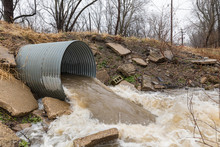 Closeup Motion Blur Of Storm Water Runoff Flowing Through Metal Drainage Culvert Under Road. January Storms Brought Heavy Rain And Flash Flooding To Illinois