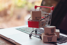 Shopping Online Concept - Parcel Or Paper Cartons With A Shopping Cart Logo In A Trolley On A Laptop Keyboard. Shopping Service On The Online Web. Offers Home Delivery...