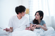 © kwanchaift - young woman with scowling face sit on the bed while neglect husband playing a smartphone