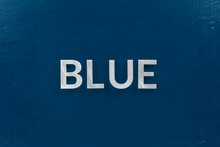 The Word Blue Laid With Silver Metal Letters On Classic Blue Painted Board Background