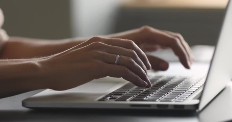female hands typing on laptop at desk, close up view