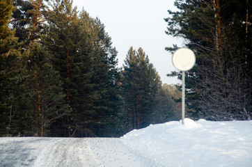 white sign stands near the road in winter