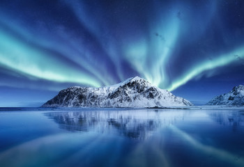 aurora borealis, lofoten islands, norway. northen lights, mountains and reflection on the water. win