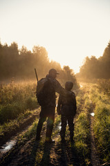 father teaches his grandson to hunt in a woods