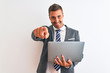 © Krakenimages.com - Young handsome business man working using computer laptop over isolated background pointing with finger to the camera and to you, hand sign, positive and confident gesture from the front