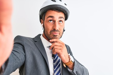 Canvas Print - Young handsome business man wearing bike helmet taking a selfie over isolated background serious face thinking about question, very confused idea