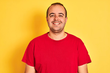 Poster - Young man wearing red casual t-shirt standing over isolated yellow background with a happy face standing and smiling with a confident smile showing teeth