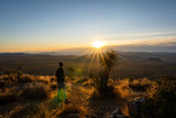Fototapeta Kosmos - Man taking in the sunrise on a solo outdoors hike in Joshua tree with lens flare from sun | Joshua Tree Hiking
