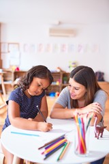 Poster - Beautiful teacher and toddler girl drawing draw using colored pencils at kindergarten