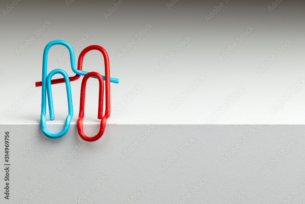 Paper clips in the form of a hugging couple in love for the concept of happy relationship - obrazy, fototapety, plakaty 