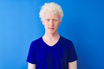 Wall Mural - Young albino blond man wearing casual t-shirt standing over isolated blue background with serious expression on face. Simple and natural looking at the camera.