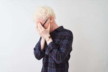 Wall Mural - Young albino blond man wearing casual shirt and glasses over isolated white background with sad expression covering face with hands while crying. Depression concept.