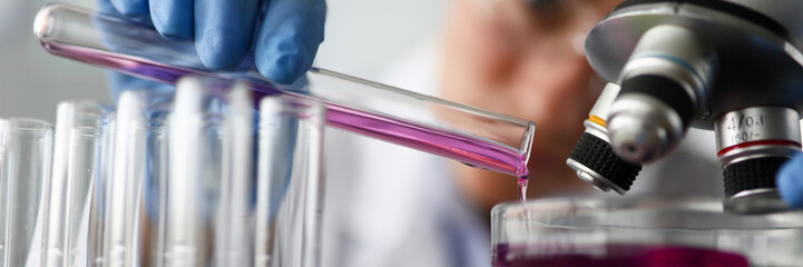 Female chemist holds test tube of glass in hand closeup overflows liquid solution potassium permanganate. Conducts an analysis reaction takes various versions reagents using chemical manufacturing